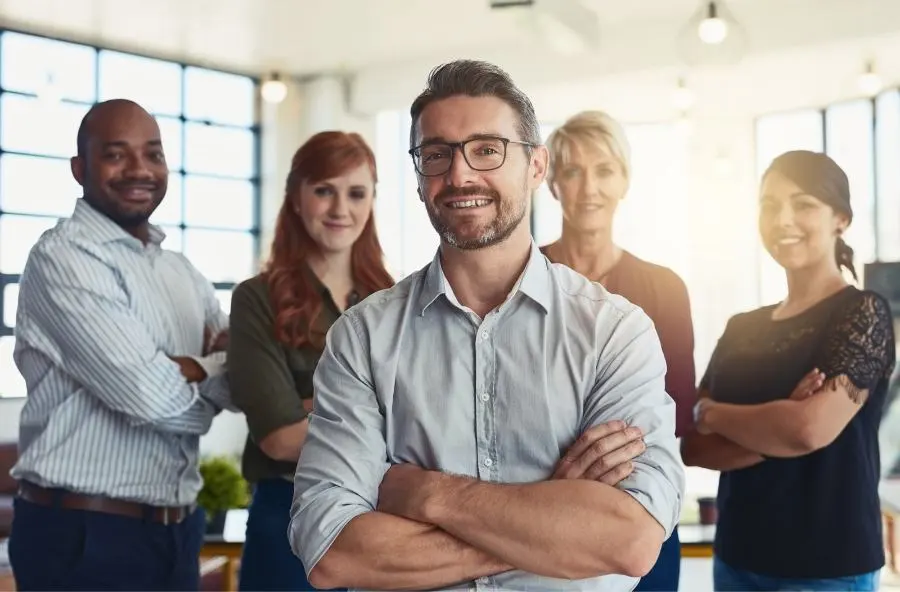 Immagine di una manager sorridente con il suo team sullo sfondo.